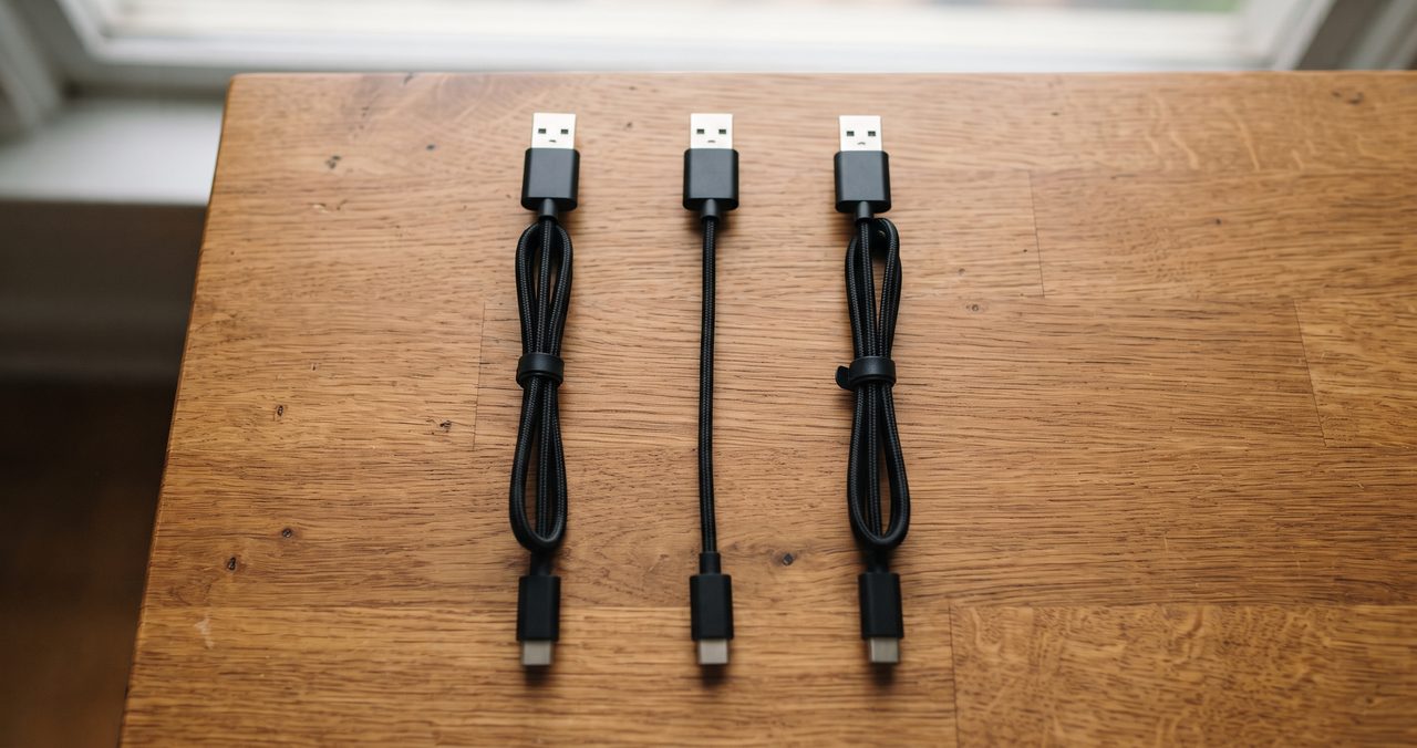 見た目がよく似た複数のUSBケーブルが机の上に並べて置かれている物撮り写真、充電専用ケーブルとデータ通信対応ケーブルの見分けにくさを表すイメージ