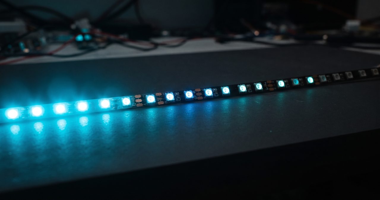 薄暗い室内でフルカラーLEDテープの一部が水色を中心にグラデーション状に光が流れているクローズアップ写真