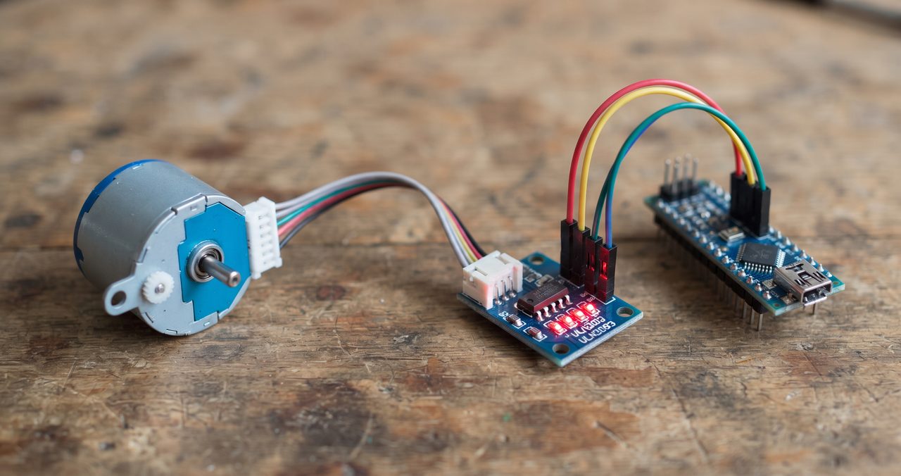 小さな円筒形のステッピングモーターとドライバ基板が、ジャンパー線でArduino互換ボードに接続されている物撮り写真